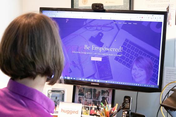 Mujer de espaldas mirando pantalla de computadora con texto "Be Empowered!"