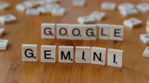 Letras de scrabble forman "GOOGLE GEMINI" sobre un fondo de madera.